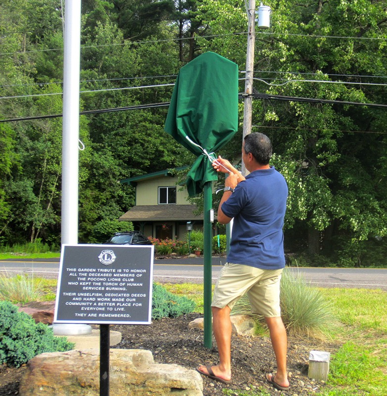Sean Naughton, president of the Pocono Lions Club, starts to unveil the Tobyhanna Township historical marker.